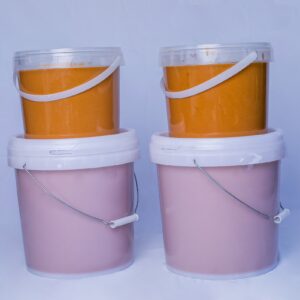 Deux colonnes de seaux de pâte d'arachide, avec un seau de 10kg soutenant un seau de 5kg de pâte d'arachide.