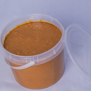 Seau ouvert de 5 litres de pâte d'arachide 'Saveur d'Afrique', révélant le produit 100% naturel, sur un fond uni.