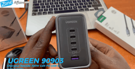 Chargeur UGREEN Nexode 300W avec ports USB-C et USB-A tenu en main devant un ordinateur portable.