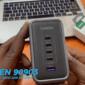 Chargeur UGREEN Nexode 300W avec ports USB-C et USB-A tenu en main devant un ordinateur portable.